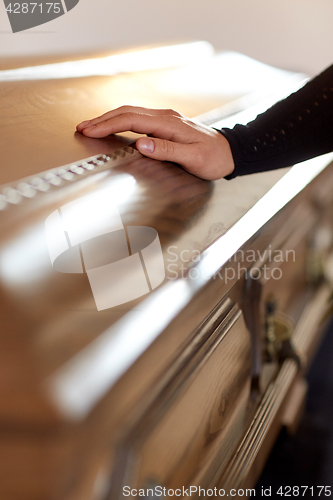 Image of woman hand on coffin lid at funeral in church