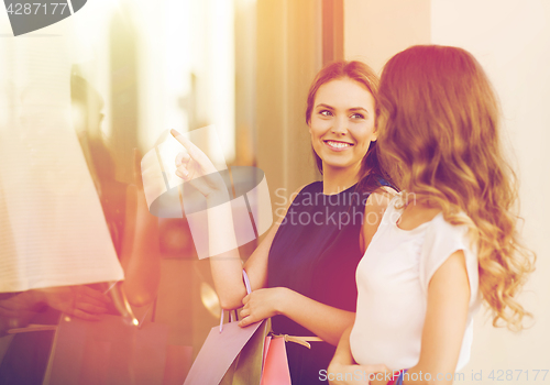 Image of happy women with shopping bags at shop window