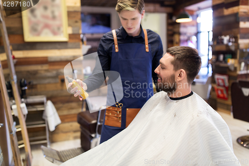 Image of barber showing hair styling spray to male customer