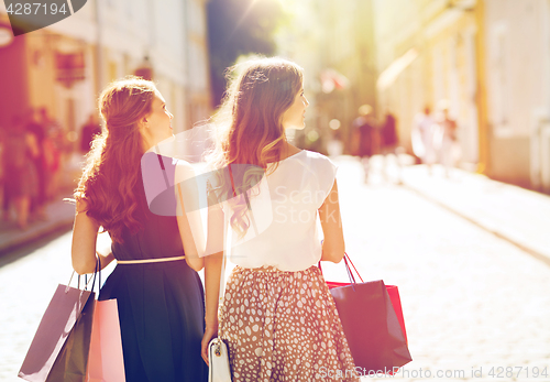 Image of happy women with shopping bags walking in city 
