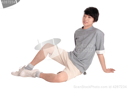 Image of Young Asian man sitting on floor.