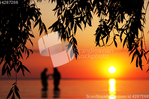 Image of Blurred silhouette of young couple in love, standing in the sea 