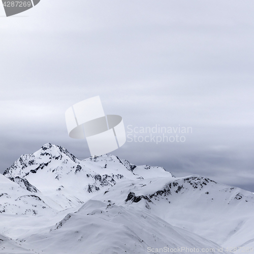 Image of Gray snowy mountains in evening