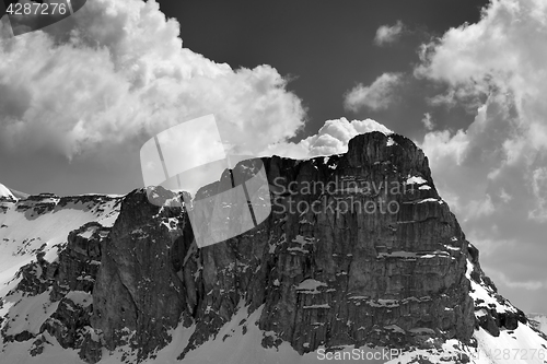 Image of Black and white view on snow rocks and sky with clouds