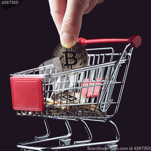 Image of hand throws a bitcoin into trolley.