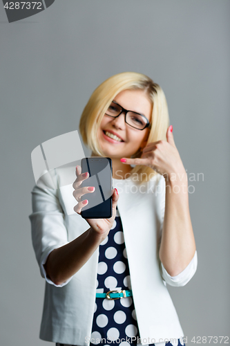 Image of Blonde with phone shows shaka