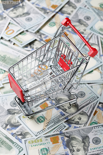 Image of Empty trolley standing on heap of dollars