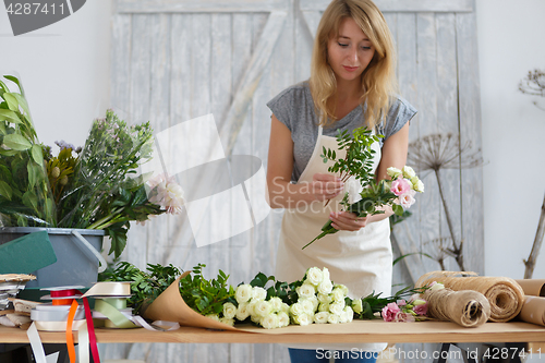 Image of Young woman florist makes bouquet