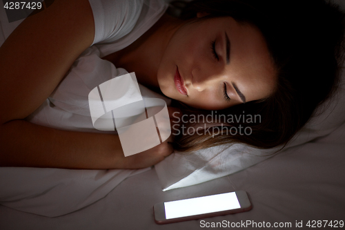 Image of woman with smartphone sleeping in bed at night