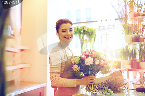 Image of smiling florist woman making bunch at flower shop