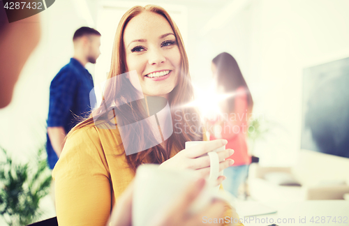 Image of happy creative team drinking coffee at office