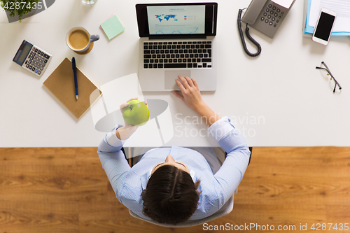 Image of businesswoman with apple and laptop at office