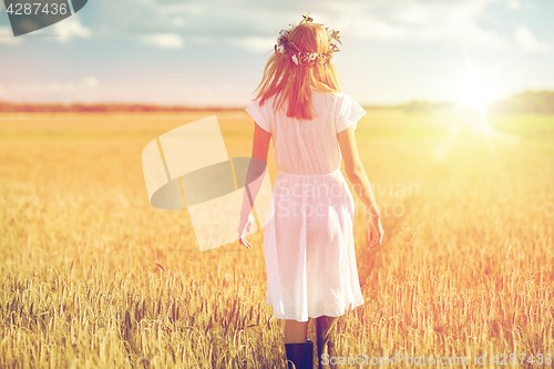 Image of happy young woman in flower wreath on cereal field