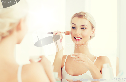 Image of woman with makeup brush and powder at bathroom