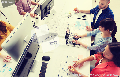 Image of creative team with computers, blueprint at office