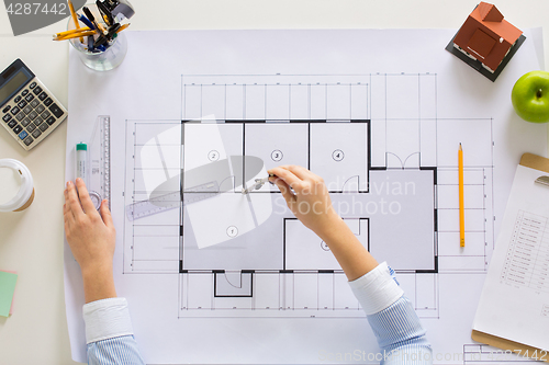 Image of hands with compass measuring blueprint at office