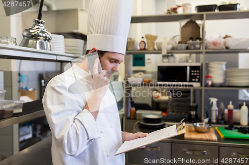 Image of chef cook calling on smartphone at restaurant kitchen