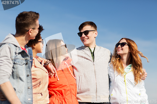 Image of happy teenage friends in shades talking on street