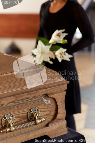 Image of woman with flowers and coffin at funeral