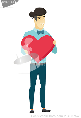 Image of Asian business man holding a big red heart.