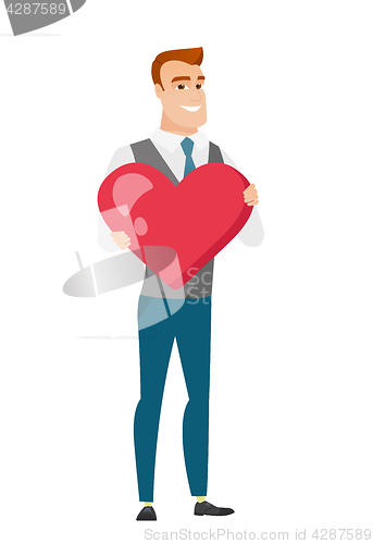 Image of Caucasian business man holding a big red heart.