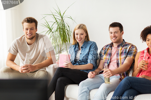 Image of happy friends with popcorn watching tv at home