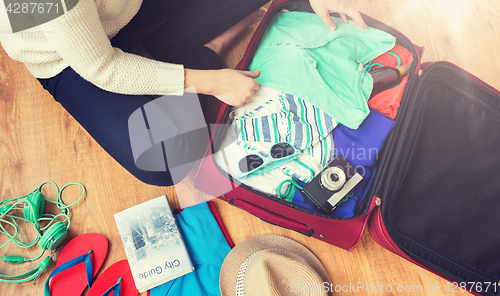 Image of close up of woman packing travel bag for vacation