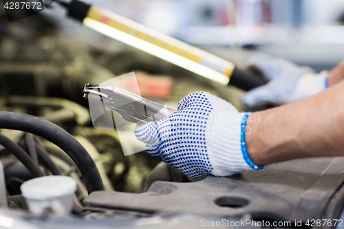 Image of mechanic man with pliers repairing car at workshop