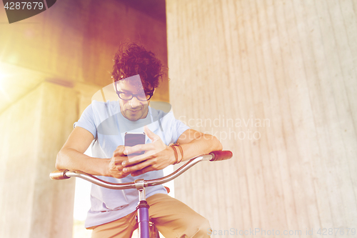 Image of man with smartphone and fixed gear bike on street