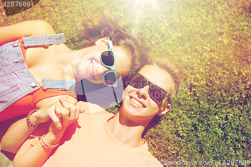 Image of happy teenage couple lying on grass at summer