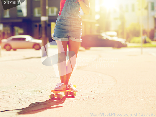 Image of teenage girl riding skateboard on city street