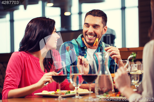 Image of happy couple with friends eating at restaurant