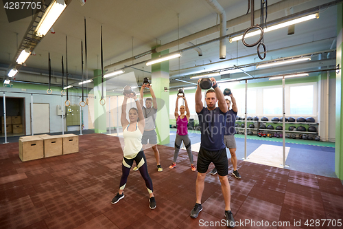 Image of group of people with kettlebells exercising in gym