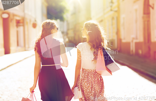 Image of happy women with shopping bags walking in city 