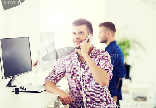 Image of happy creative man calling on cellphone at office