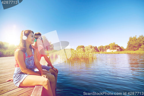 Image of happy teenage couple with earphones on river berth