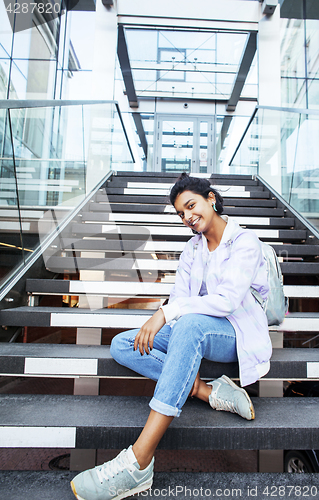 Image of young cute indian girl at university building sitting on stairs 