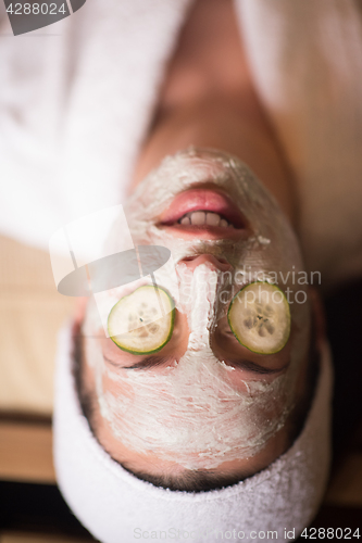 Image of woman is getting facial clay mask at spa