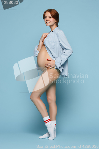 Image of Young beautiful pregnant woman standing on blue background