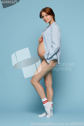 Image of Young beautiful pregnant woman standing on blue background