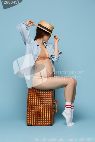 Image of Young beautiful pregnant woman sitting on blue background