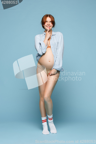 Image of Young beautiful pregnant woman standing on blue background