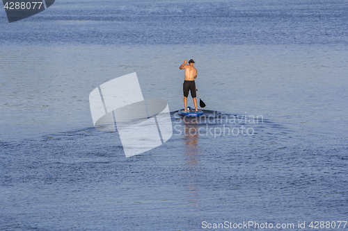 Image of Man on Paddle Board paddling out to lake