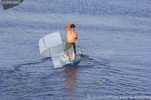 Image of Man on Paddle Board paddling out to lake