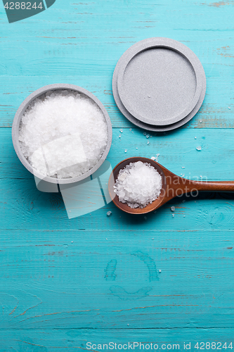 Image of sea salt in bowl and in spoon on wooden background