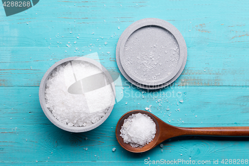 Image of sea salt in bowl and in spoon on wooden background