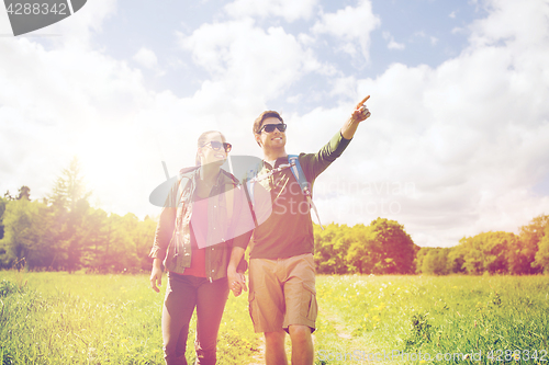 Image of happy couple with backpacks hiking outdoors