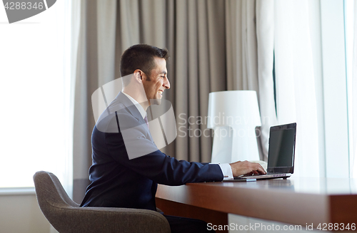 Image of businessman typing on laptop at hotel room