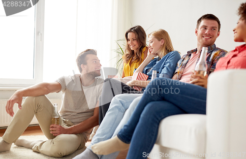 Image of happy friends with popcorn and beer at home