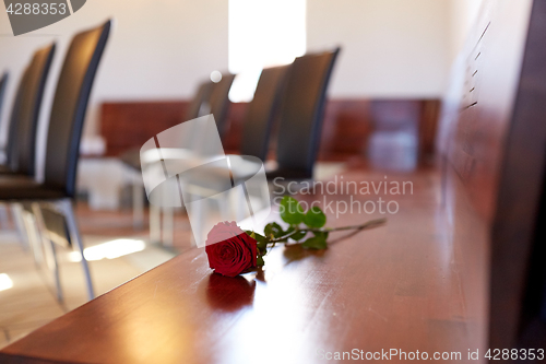 Image of red roses on bench at funeral in church